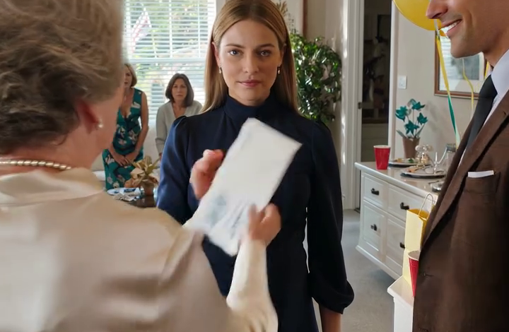 Op mijn eigen babyshower gaf mijn schoonmoeder me een witte envelop en kondigde aan: “Zevenenveertig redenen waarom mijn zoon van je zou moeten scheiden.” Terwijl vijftig mensen onder gele ballonnen lachten, protesteerde ik niet. Ik belde First National, opende mijn bankapp en zag de filiaalmanager zwijgen, bleek worden en me terug zijn kantoor in wenken.